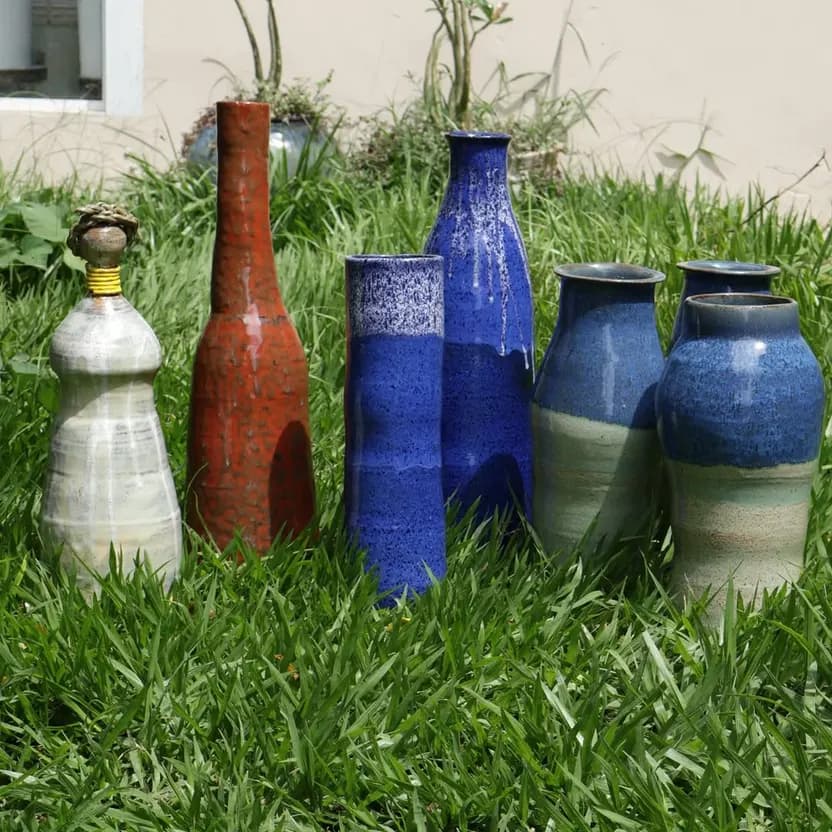 Vasos altos em azul, vermelho e branco sobre a grama